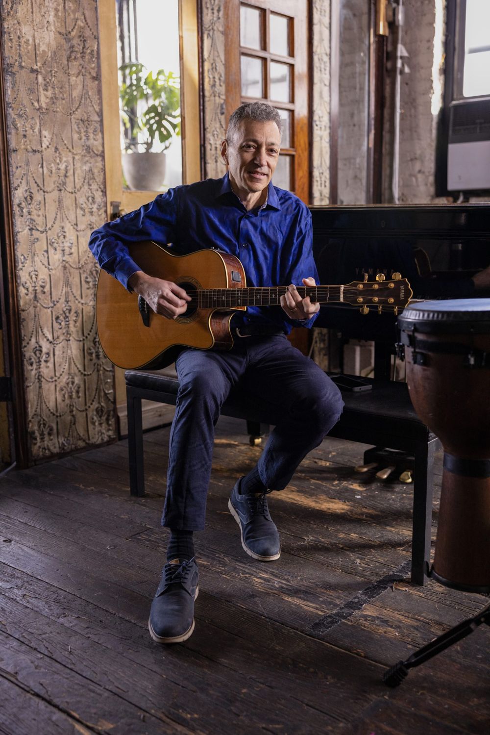 Vinny Valentino seated with an acoustic guitar