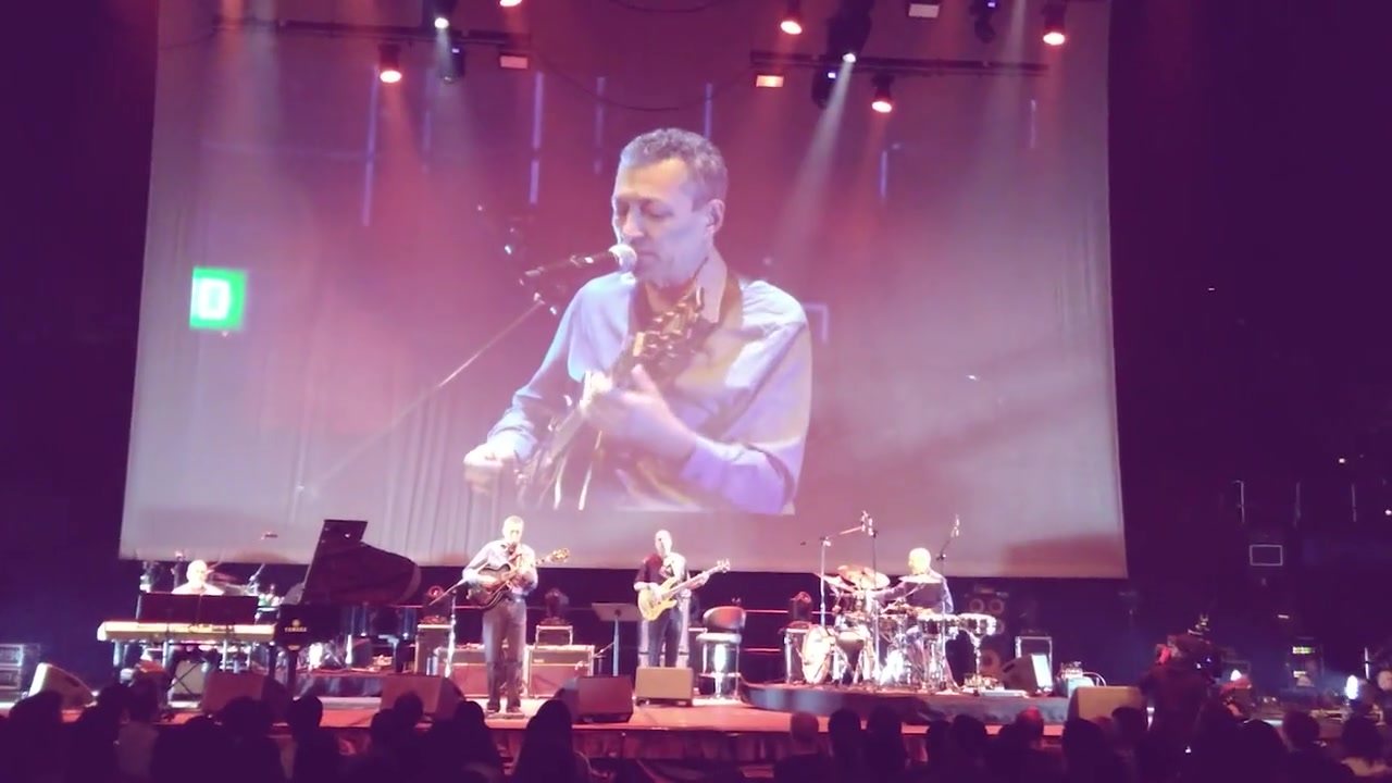 Vinny Valentino performing with his band on a concert stage before a large audience