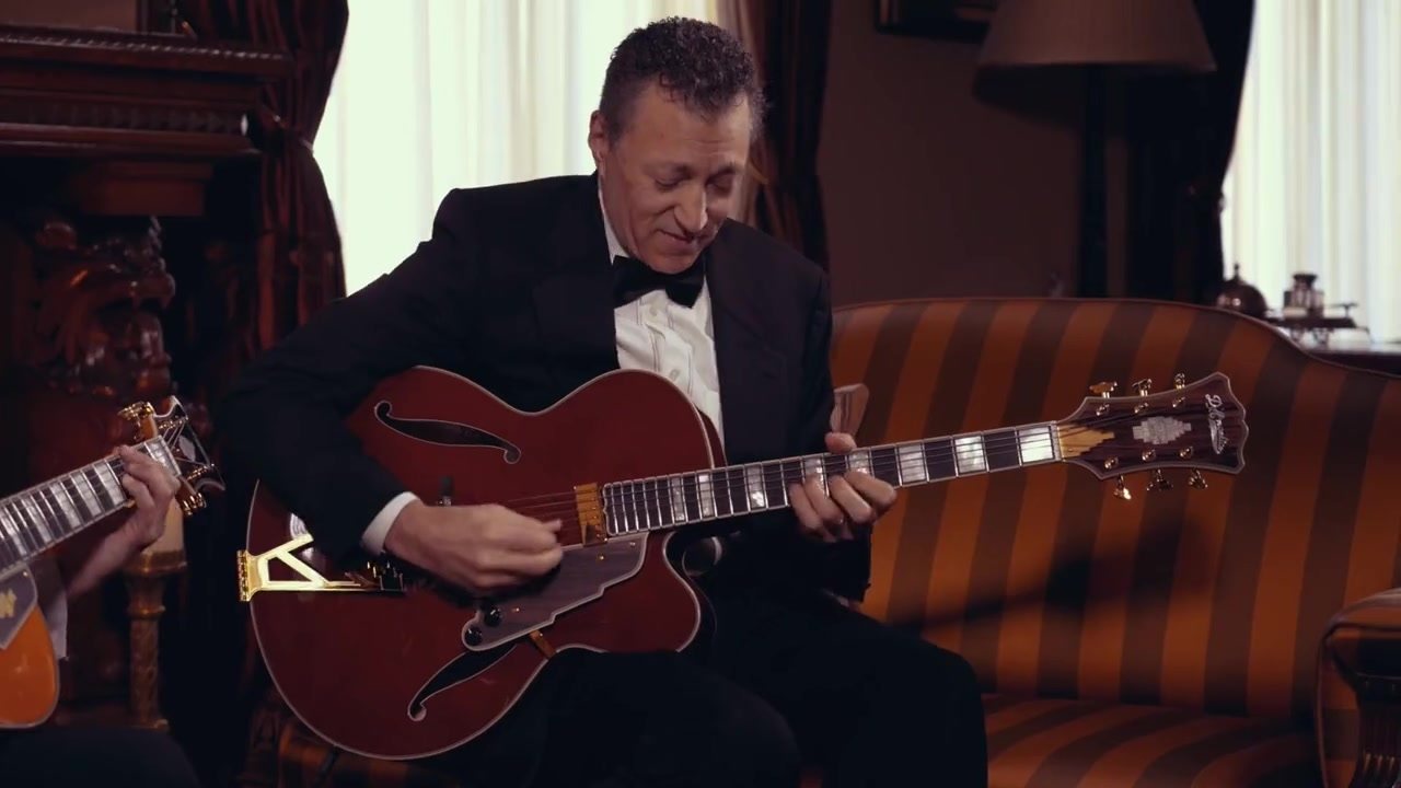 Vinny Valentino playing an archtop guitar in an elegant parlor