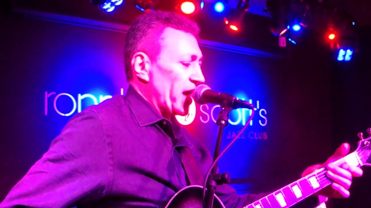 Vinny Valentino singing and playing guitar on stage at Ronnie Scott's Jazz Club in London