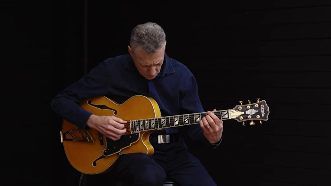 Vinny Valentino seated with an archtop guitar