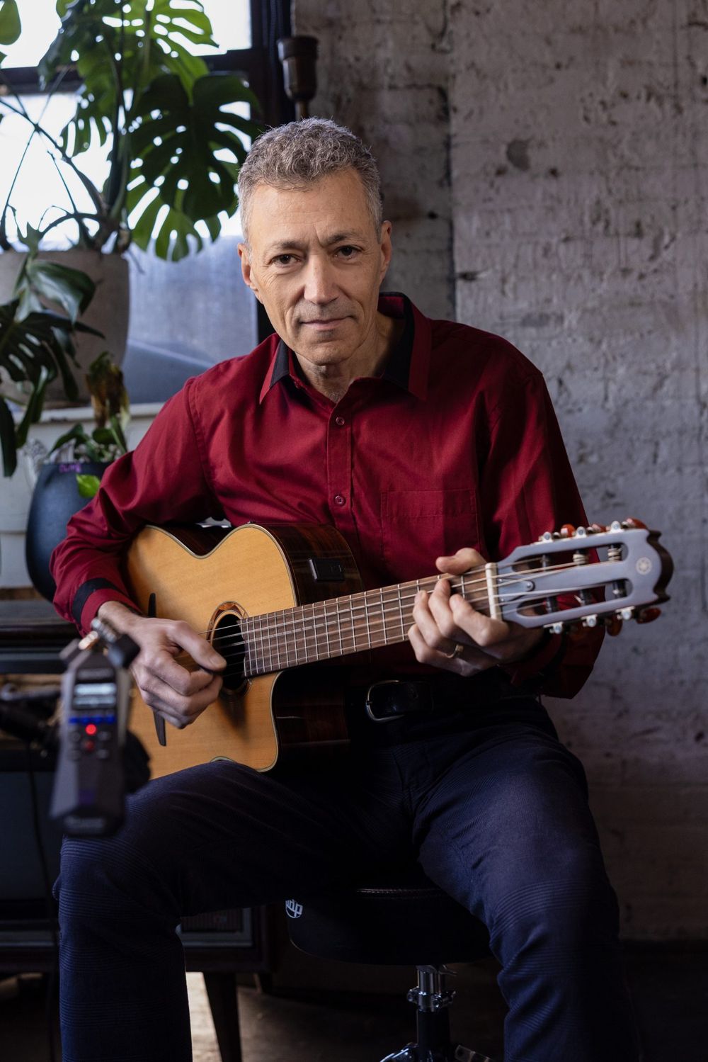 Vinny Valentino seated with a nylon-string guitar